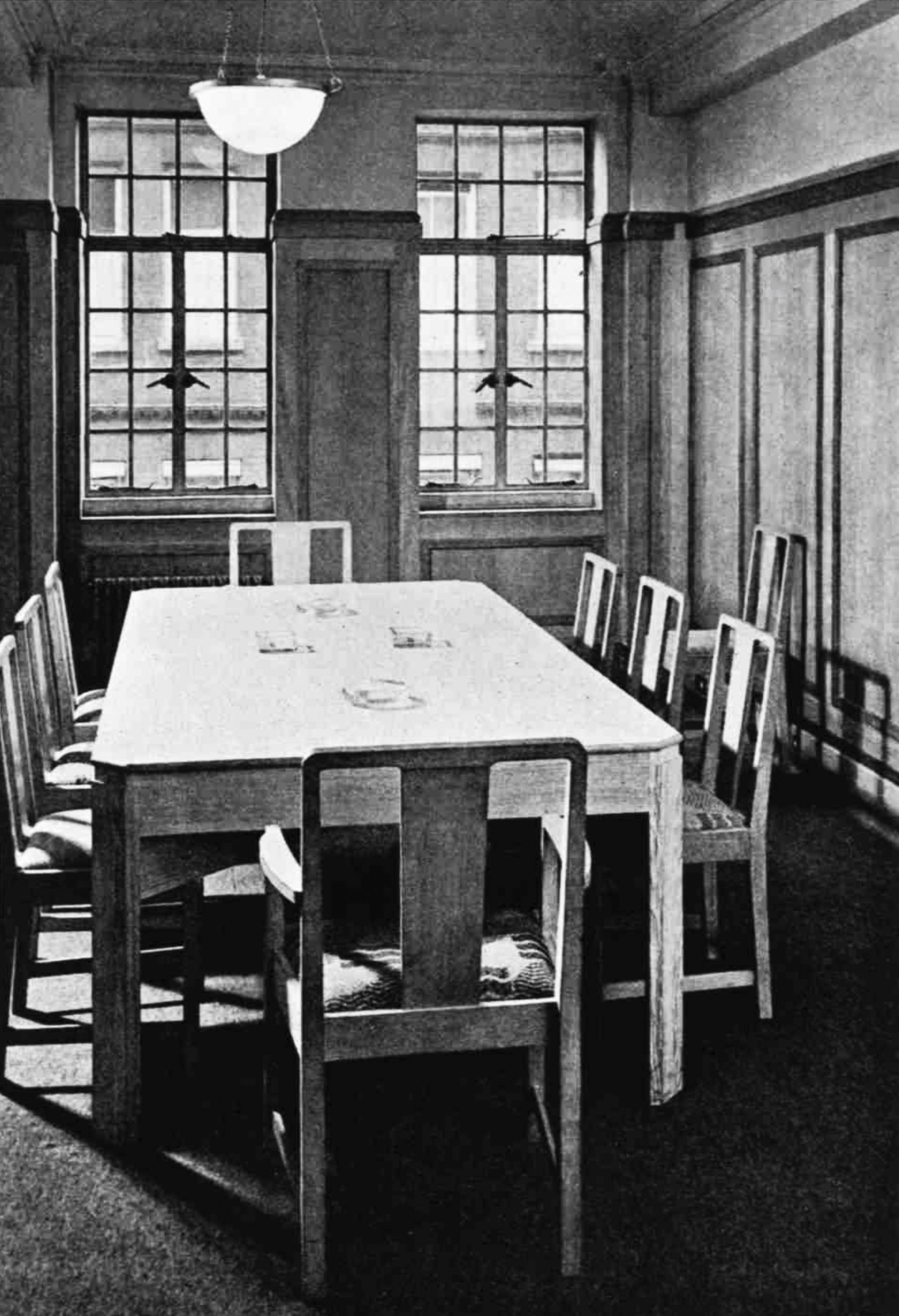 A boardroom with a table surrounded by straight-backed chairs